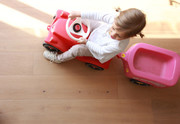Child driving a bobby car on the wooden floor.